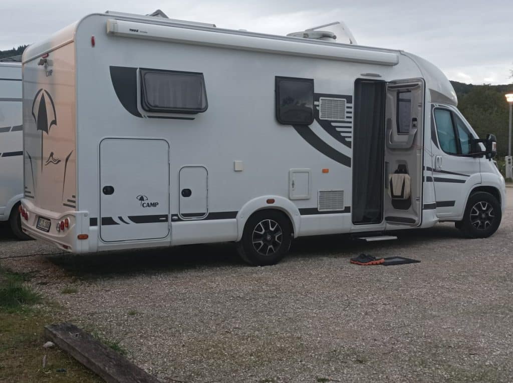Un camping-car moderne stationné en pleine nature, avec des équipements visibles à l’intérieur et une ambiance de voyage nomade.